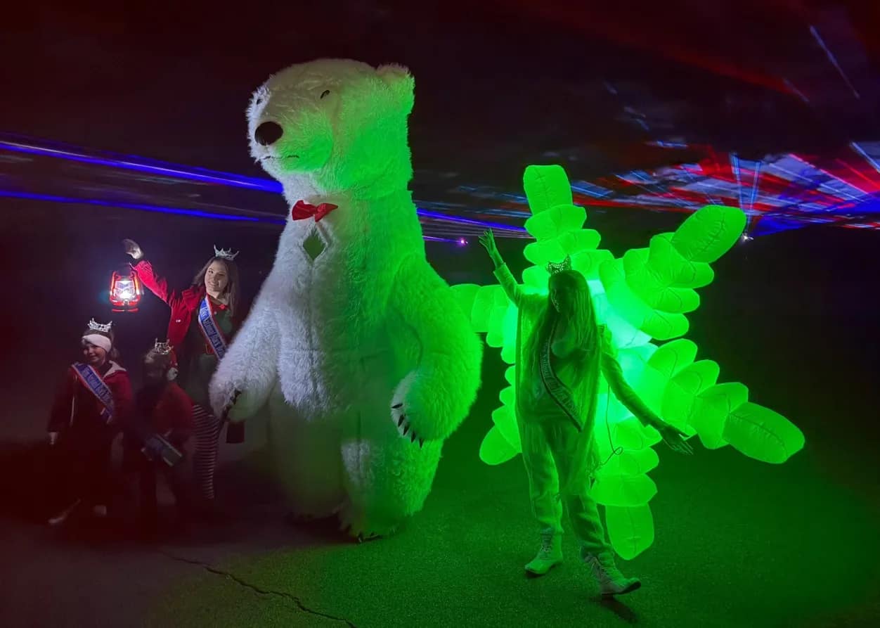 laser-2 People in costumes stand with a giant polar bear and a person in a glowing green suit under colorful lights.