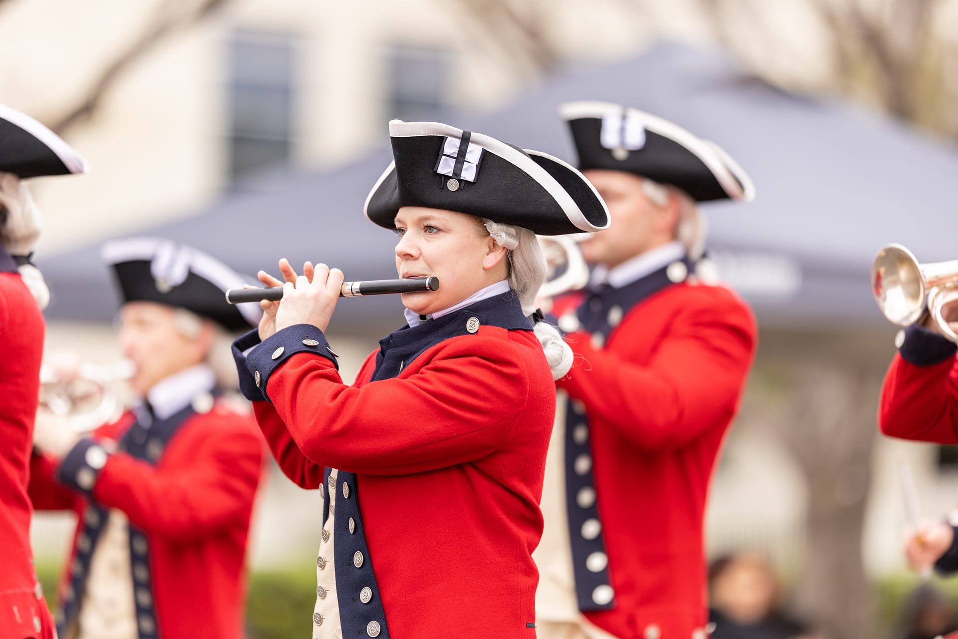 Fife-Drum-Corps-dreamstime_m_272177858 People in historical uniforms play flutes and trumpets during an outdoor event or parade.